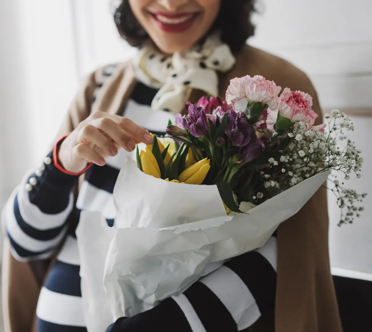 Woman in striped shirt holding bouquet of flowers