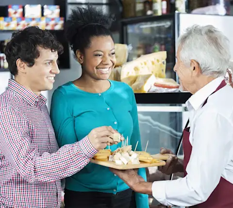 Man and woman sample cheese from platter
