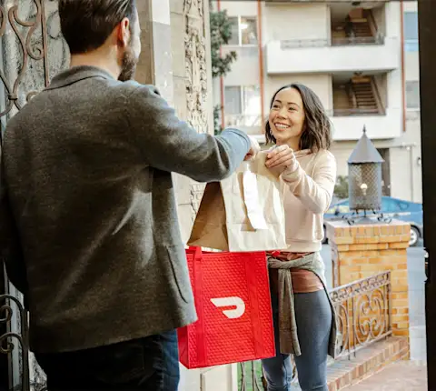 DDfW - Blog - Tips for Ordering Lunches Your Remote Team Will Love - Handing Dasher bag