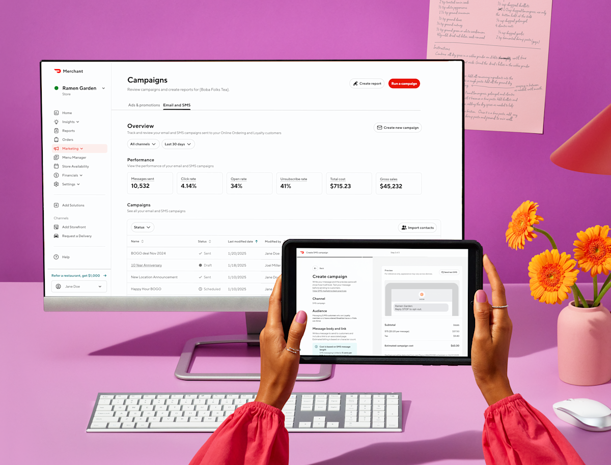 Person using DoorDash Merchant campaign dashboard on tablet and monitor with performance metrics and orange flowers nearby.