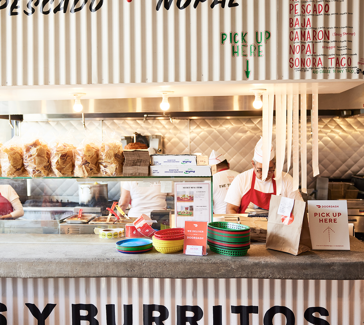 Restaurant employee working at the counter with orders ready for pickup with DoorDash
