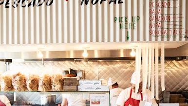 Restaurant employee working at the counter with orders ready for pickup with DoorDash