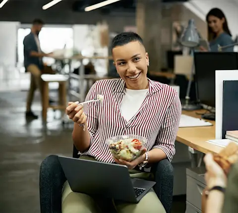 DDfB - Blog - How Eating Healthy at Work Can Improve Performance - Smiling employee with meal and laptop