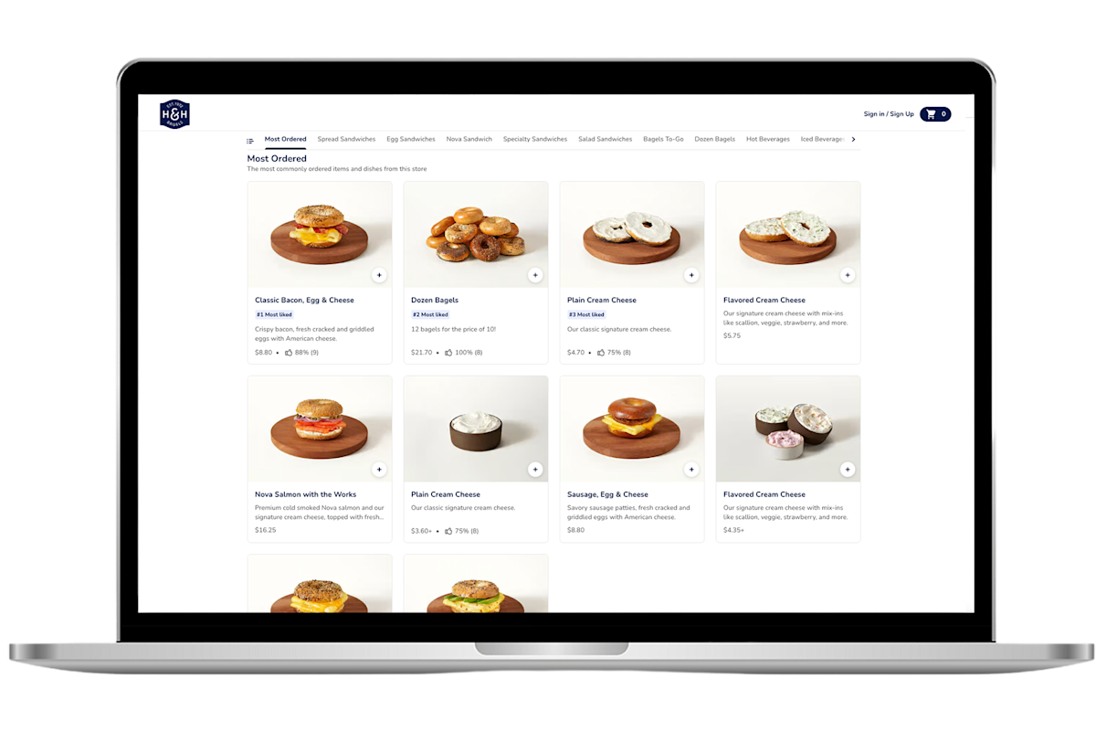 Laptop screen showing a bagel shop's online ordering menu with popular items including sandwiches, cream cheese, and dozen bagels.