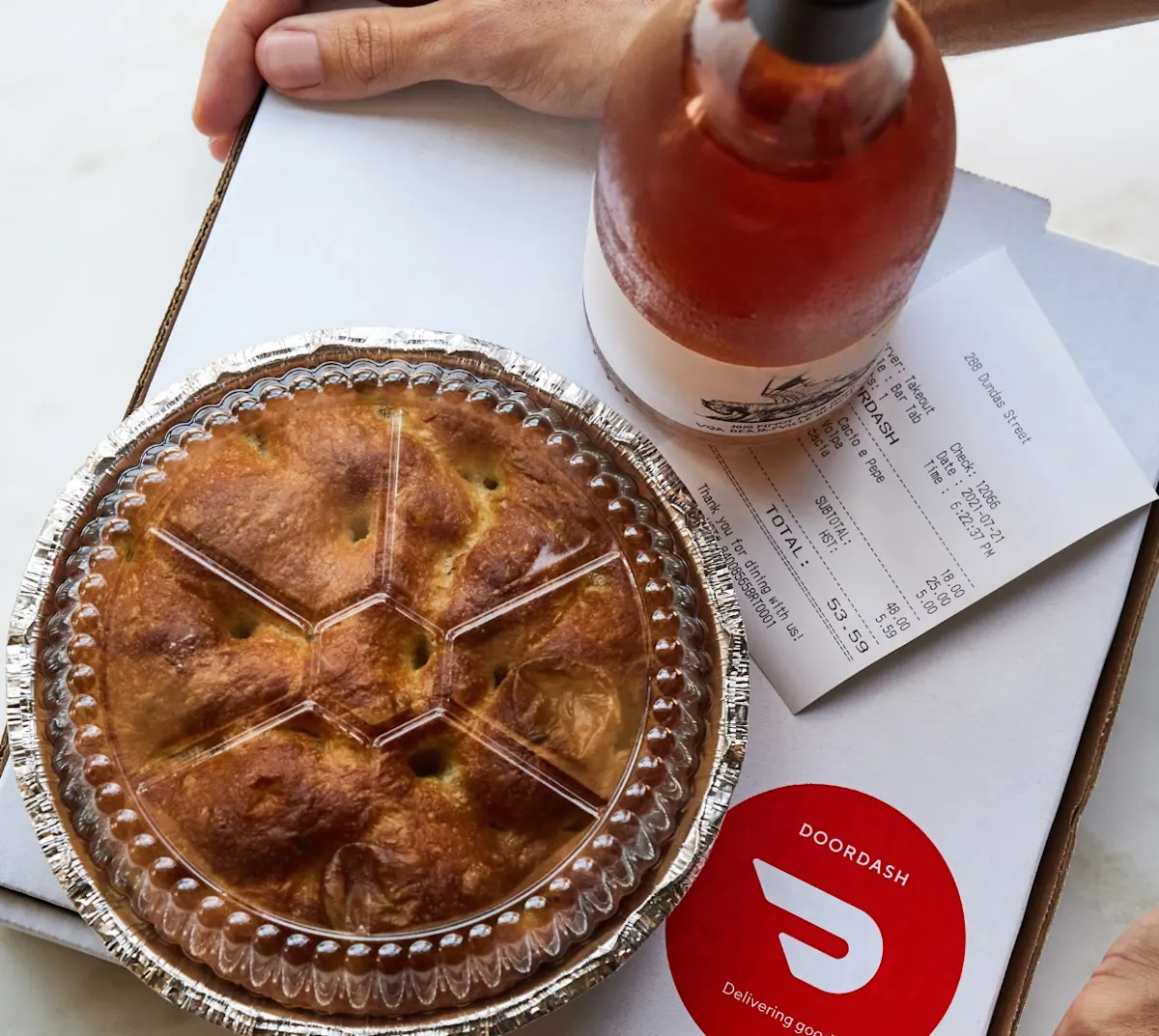 A pie with a bottle of wine ready to be delivered by DoorDash