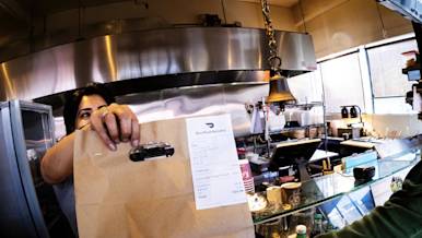 Mx Blog - Comparing In-House and Third-Party Delivery Services for Restaurants - Kitchen giving order bag to Dasher