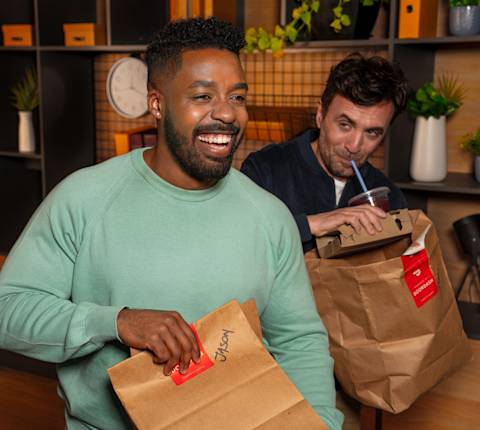 DDfB two men receiving DoorDash bags, man drinking