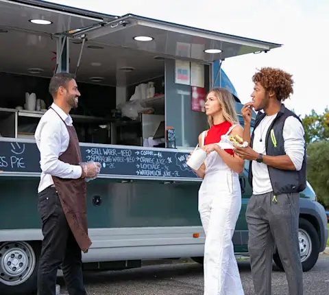 Customers enjoying fast food at an outdoor food truck with a friendly server.
