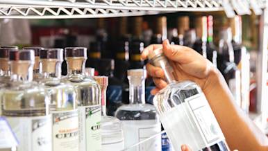 Hands holding bottle in alcohol aisle