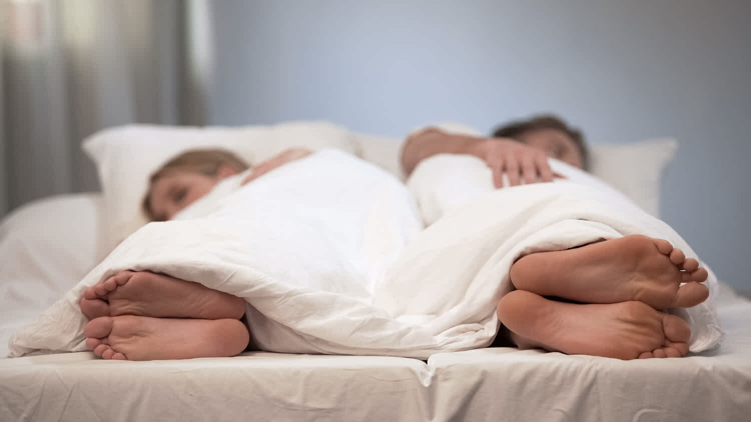couple lying in bed facing away from each other