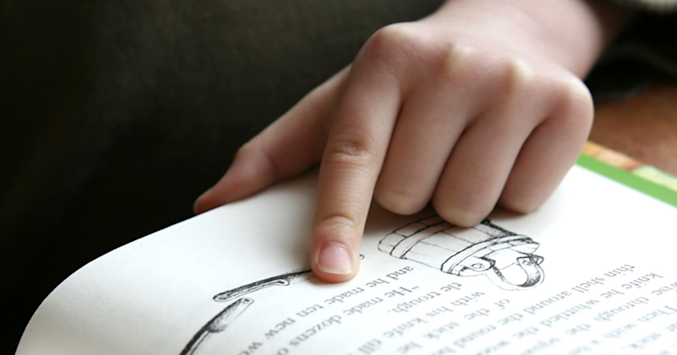 Child reading with their finger.