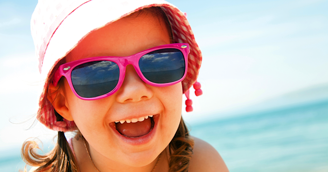 child wearing sunglasses and sun hat at the beach