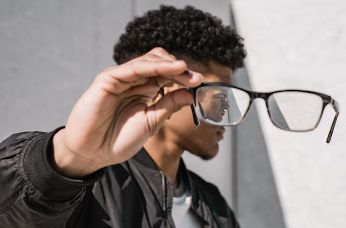 Teen boy removing glasses from face