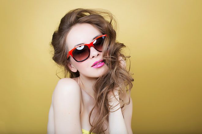 Woman wearing two toned sunglass frames on a yellow background