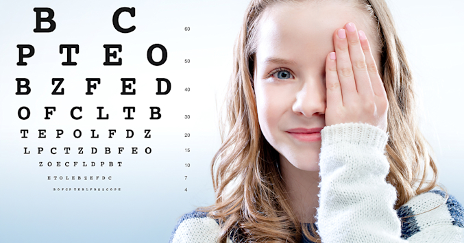 girls covers one eye and looks at eye chart