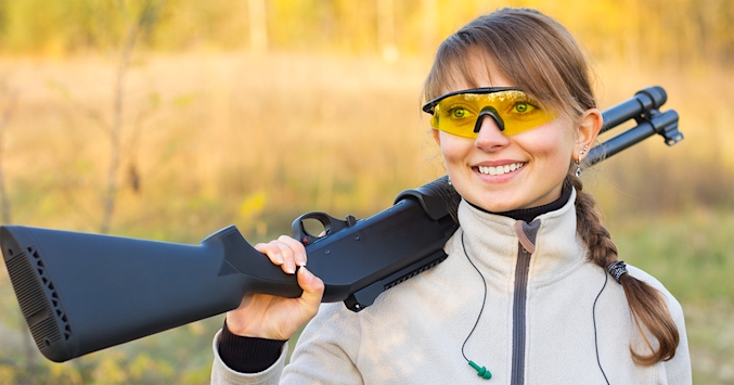 woman wearing shooting glasses and holding gun