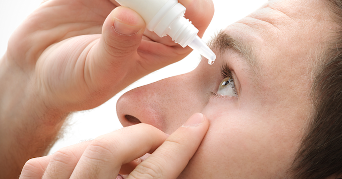 man using eye drops
