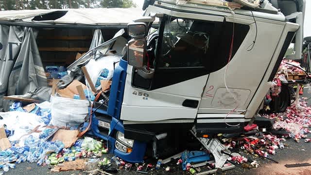 Das Führerhaus eines Lkw ist zerstört durch einen Unfall, überall darum herum liegen Getränkeflaschen.