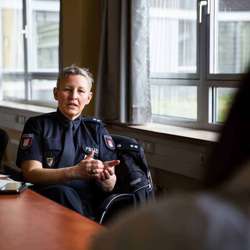Eine Polizistin sitz in einem Besprechungszimmer und unterhält sich mit der sympathischen Redakteurin.  