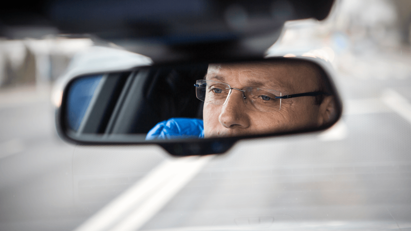 Man sieht das Gesicht von Gustav Engljähringer im Rückspiegel seines Autos.
