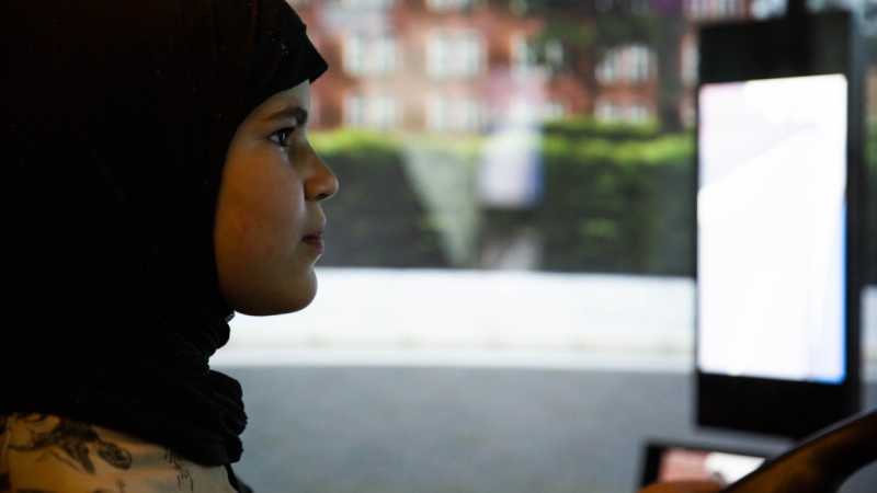 Ein Mädchen schaut konzentriert auf einen Bildschirm des Lkw-Simulators.