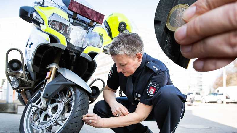 Eine Polizistin prüft mit Hilfe einer 1-Euro-Münze das Reifenprofil ihres Motorrads.