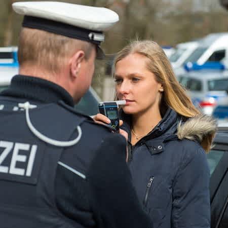 Ein Polizist lässt eine Frau in einen Alkoholtest pusten.