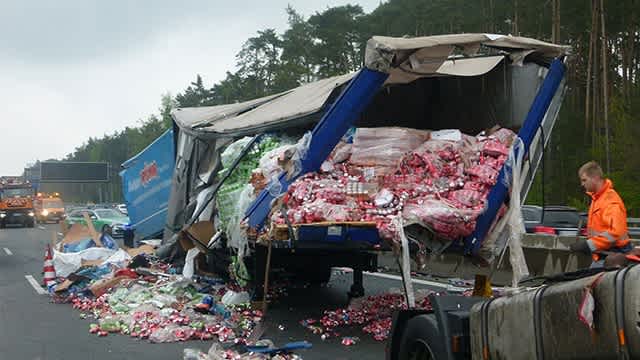 Das Bild zeigt einen verunglückten Lkw, dessen Ladung, Getränkeflaschen, auf der kompletten Fahrbahn verteilt ist.