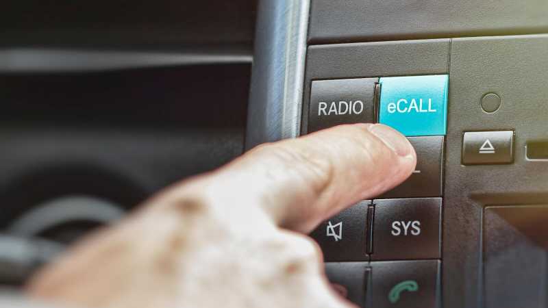 Eine Person drückt den eCall-Knopf im Cockpit eines Autos.