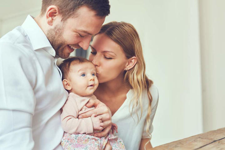 A father and mother hold their newborn baby.