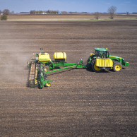 Side view of a tractor planting in an open field
