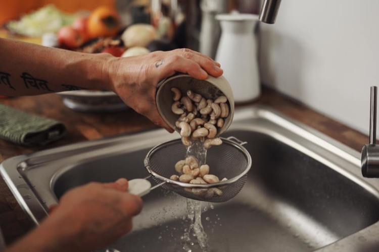 Person washing cashews in sink