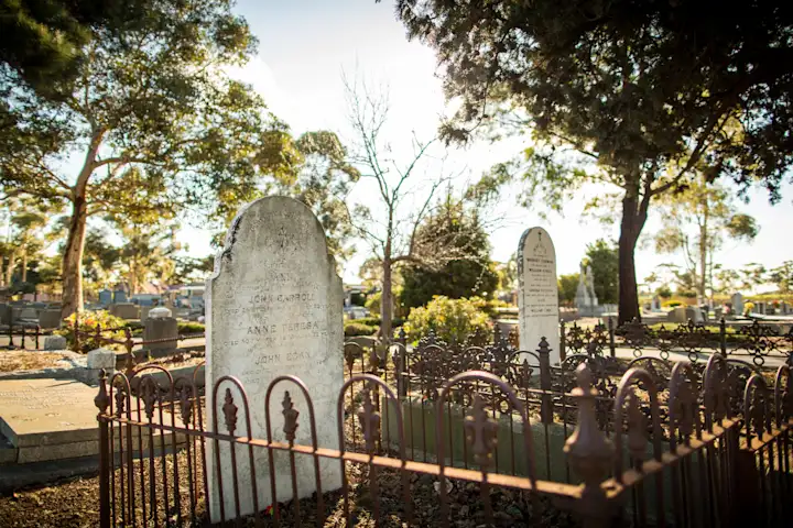 Historic stone monument and ornamental iron fence with surrounding trees, Keilor Cemetery