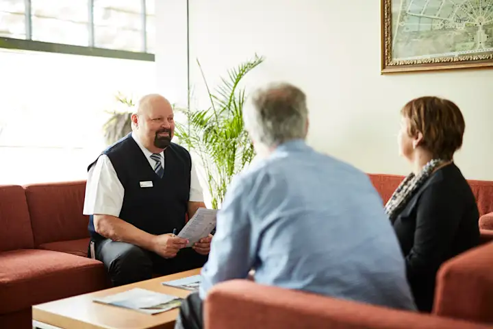 Male staff member meeting with customers sitting on a couch