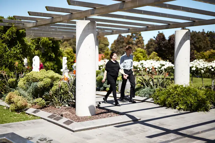 Man and woman walking under an architectural arbour at Altona Memorial Park