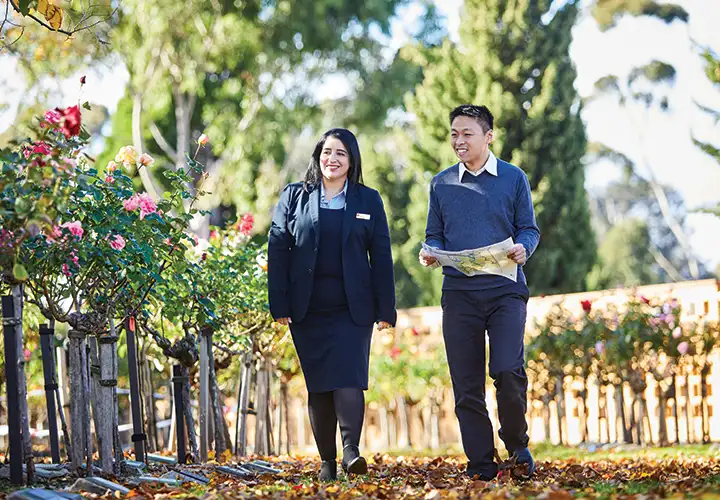 Staff member showing customer a blooming rose memorial at Fawkner Memorial Park