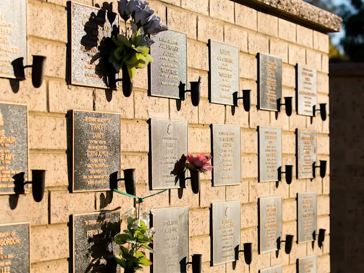 Bronze memorial plaques on a niche wall at Fawkner Memorial Park