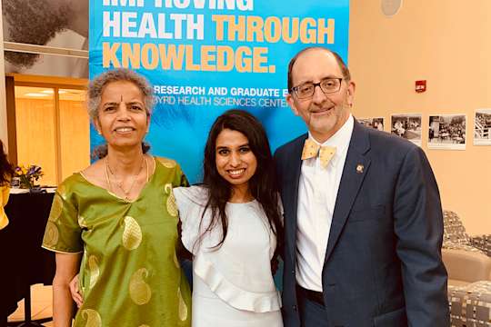 Pharmacy Dean William Petros poses for a photo with a PhD student and faculty member