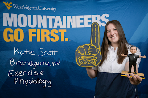 Katie Scott, an Exercise Physiology major from Brandywine, WV, wears a Mountaineer Maniacs foam finger and holds a Bob Huggins figurine.