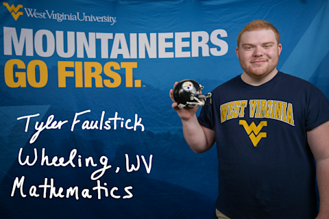 Tyler Faulstick, a Mathematics major from Wheeling, WV, wears a blue WVU T-shirt and holds a Pittsburgh Steelers mini-helmet.