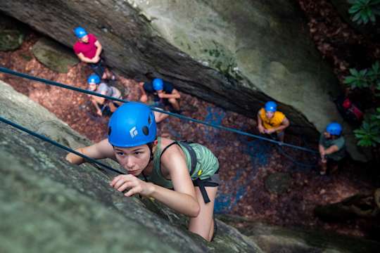 A student ascends a rock face at Coopers Rock.