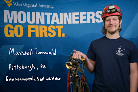 Maxwell Turnwald, an Environmental, Soil and Water major from Pittsburgh, PA, wears a WV Student Grotto shirt and hardhat. He is holding gear used for caving.