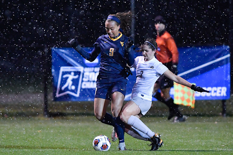 WVU women's soccer player battles for control of the ball as rain falls at Dick Dlesk Stadium