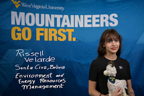 Rissell Velarde, an Environment and Energy Resources major from Santa Cruz, Bolivia, holds an alpaca stuffed animal wearing a WVU bandana.