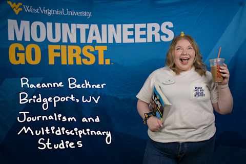 Raeanne Beckner, a Journalism and Multidisciplinary Studies major from Bridgeport, WV, balances a tiny duck figurine on her head and smiles. She is wearing a "Meet Me on High Street" shirt and holds an LSAT prep book and a Dunkin' drink.