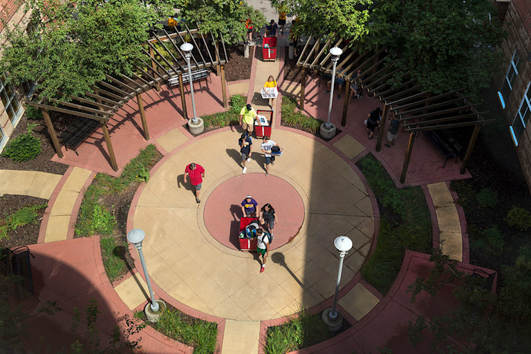 Parents and students use carts to push belongings through the courtyard of Honors Hall.