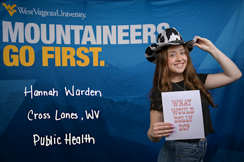 Hannah Warden, a Public Health major from Cross Lanes, WV, wears a black and white cowboy hat and holds a "What Would Dolly Do" sign.