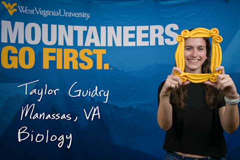 Taylor Guidry, a Biology major from Manassas, VA, smiles while looking through a gold picture frame.