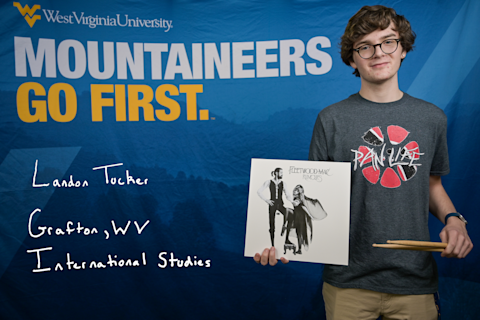 Landon Tucker, an International Studies major from Grafton, WV, wears a "Pan Life" T-shirt and holds a set of drumsticks and a Fleetwood Mac Rumours record.