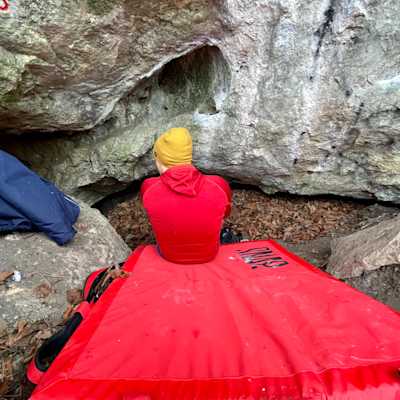 Sitting front of a cave on a bouldering mat